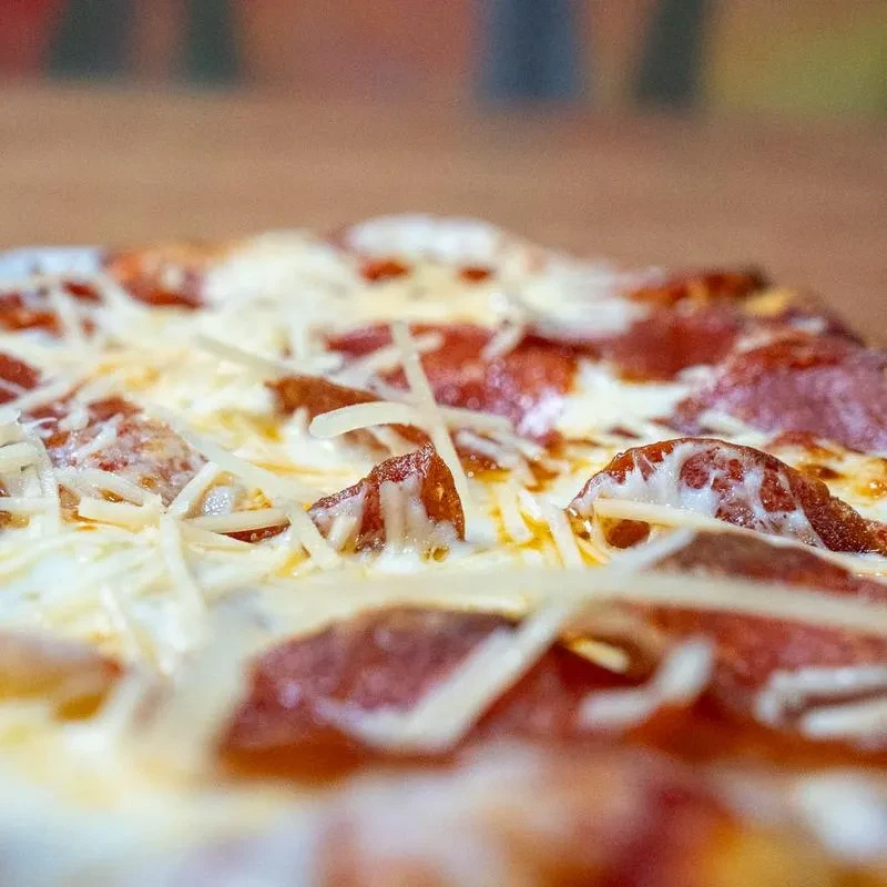 Close-up of a pepperoni pizza with shredded white cheese, some melted.