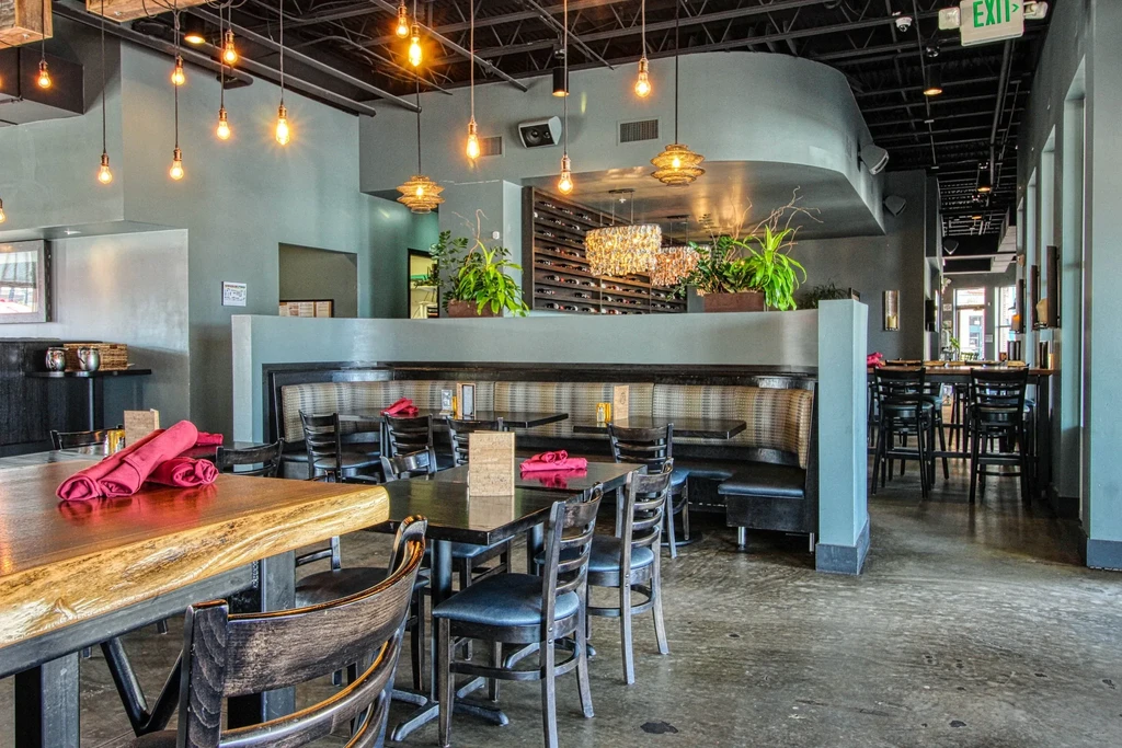 Empty modern restaurant with booth seating, Edison bulbs, and wine rack.
