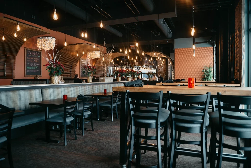 Contemporary restaurant interior with booths, communal table, and warm lighting.