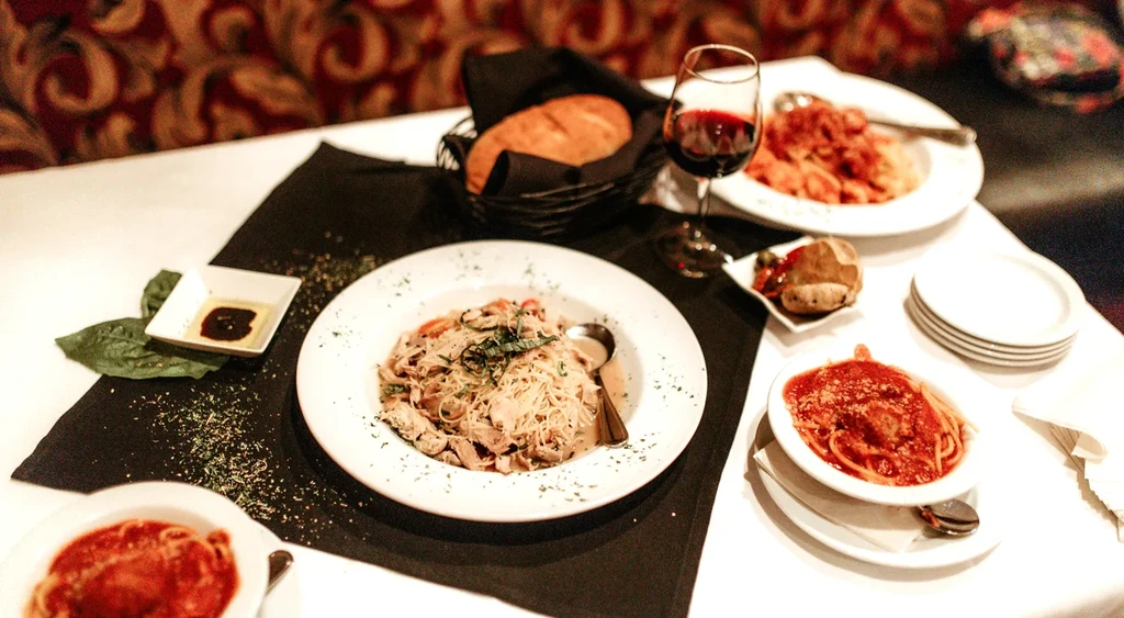 Italian pasta dinner with bread, red wine, and olive oil.