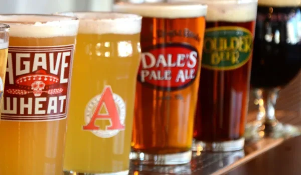 A line of branded beer glasses showcasing various colors on a bar.
