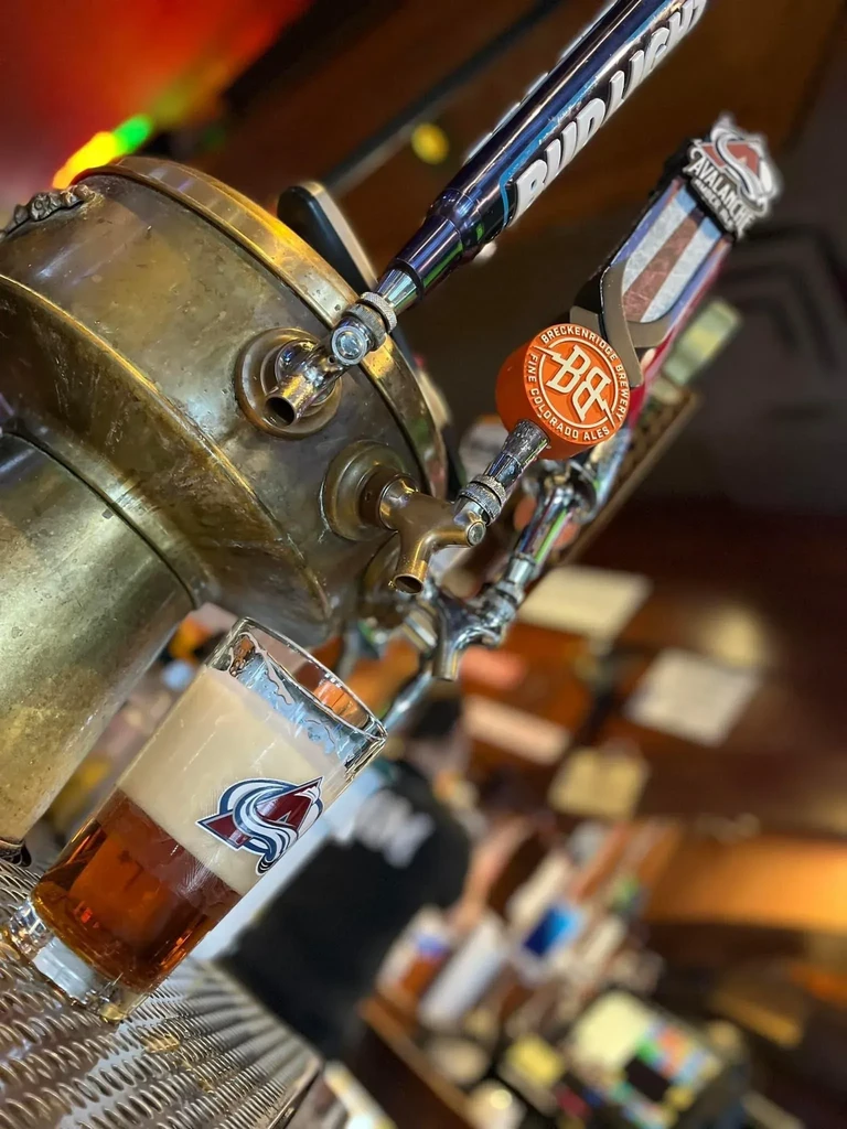 Aged brass beer taps and a glass of Breckenridge Avalanche beer.