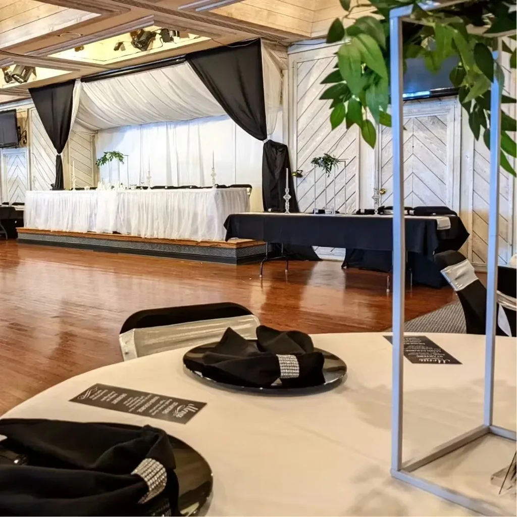 Black and white ballroom with set tables, stage, and geometric stand.