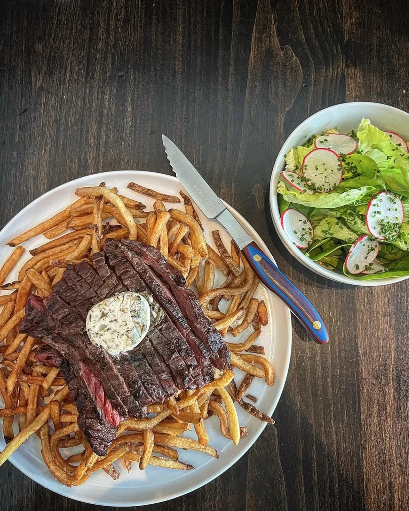 Top-down view of sliced steak, french fries, and a side salad.
