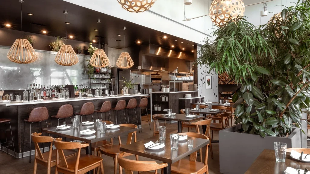 Modern, empty restaurant interior with a well-stocked bar and dining tables.
