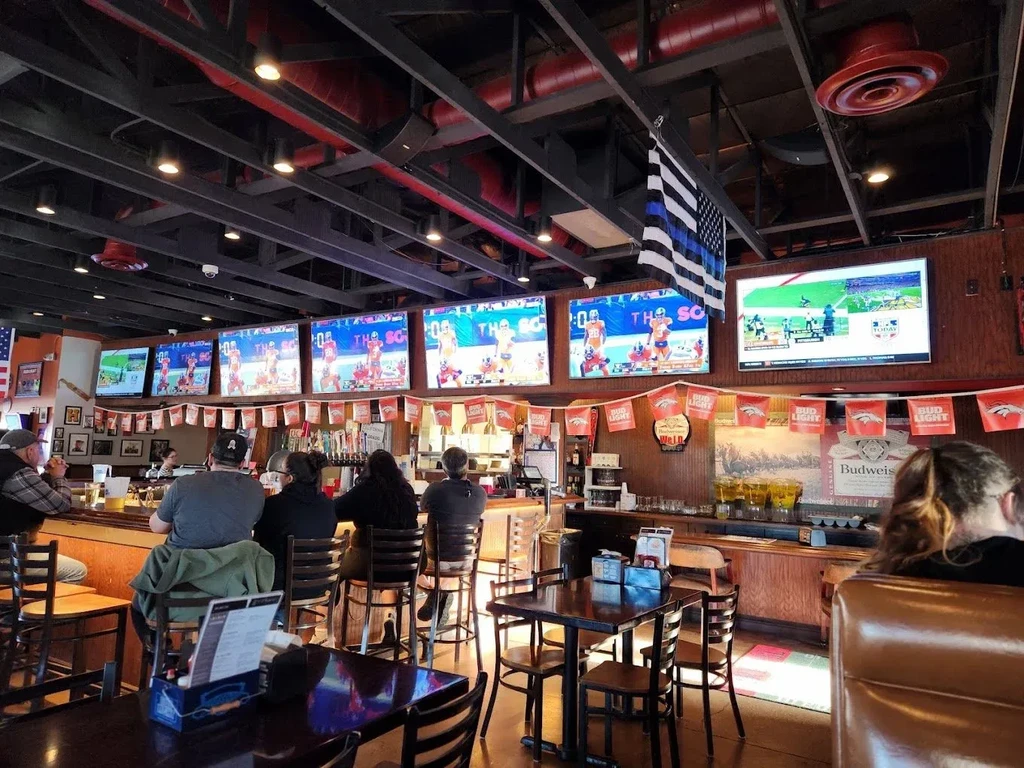 Bustling sports bar showing TVs, pennants, and a Thin Blue Line flag.