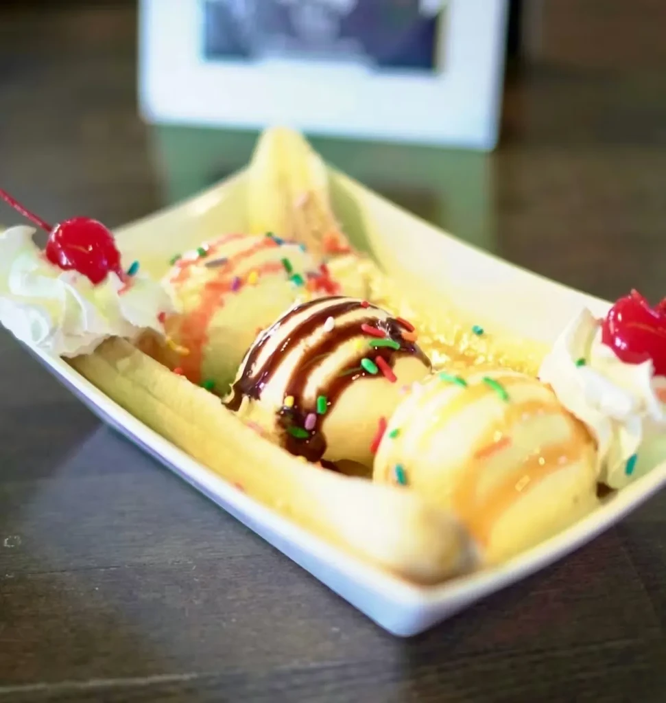 Banana split with three ice cream scoops, whipped cream, and cherries.