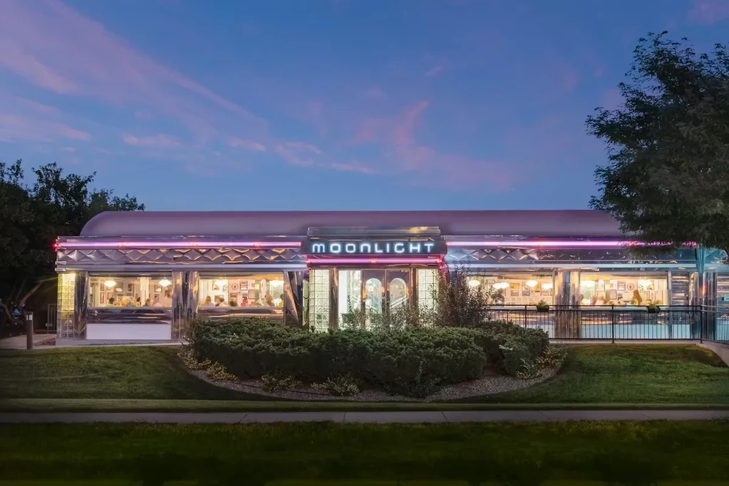"MOONLIGHT" retro diner glows with pink neon lights at twilight.