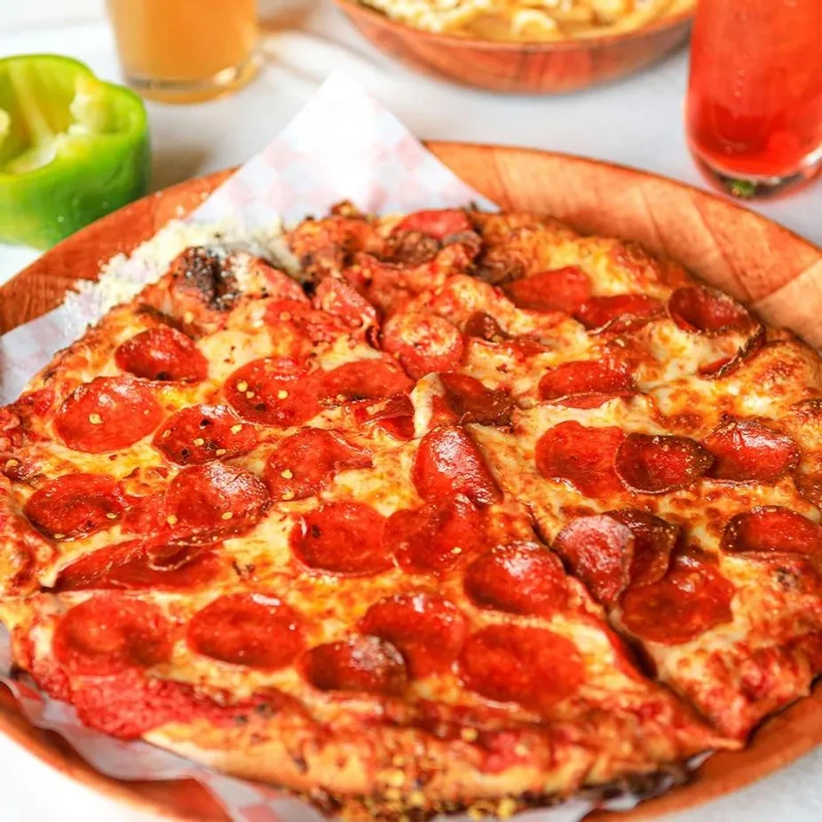Top-down view of pepperoni pizza with melted cheese in a wooden dish.