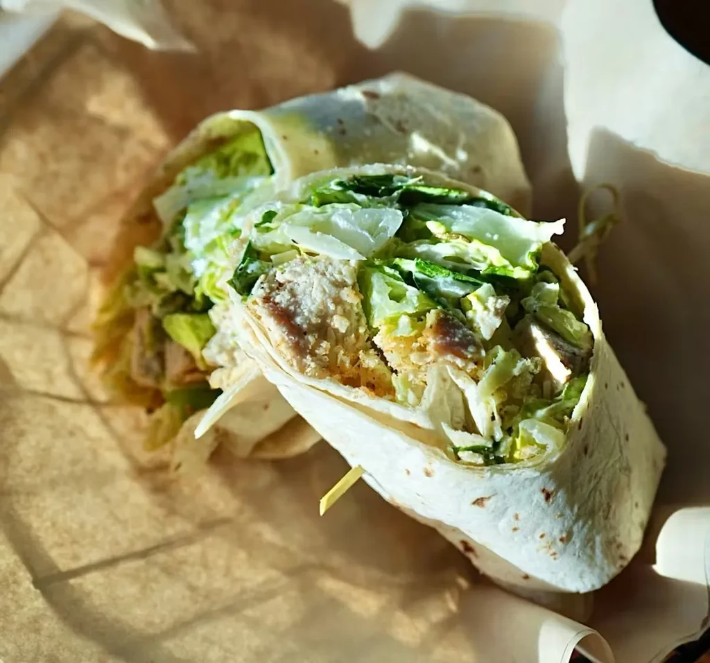 Close-up of a halved savory wrap with chicken, lettuce, and toothpick.