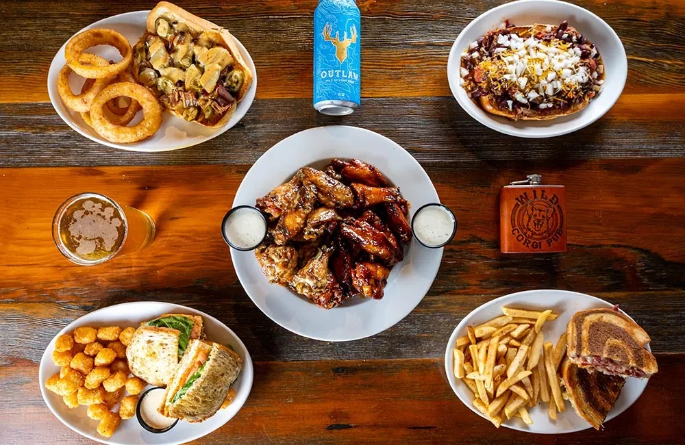 Flat lay of pub comfort food and beers on a rustic table.