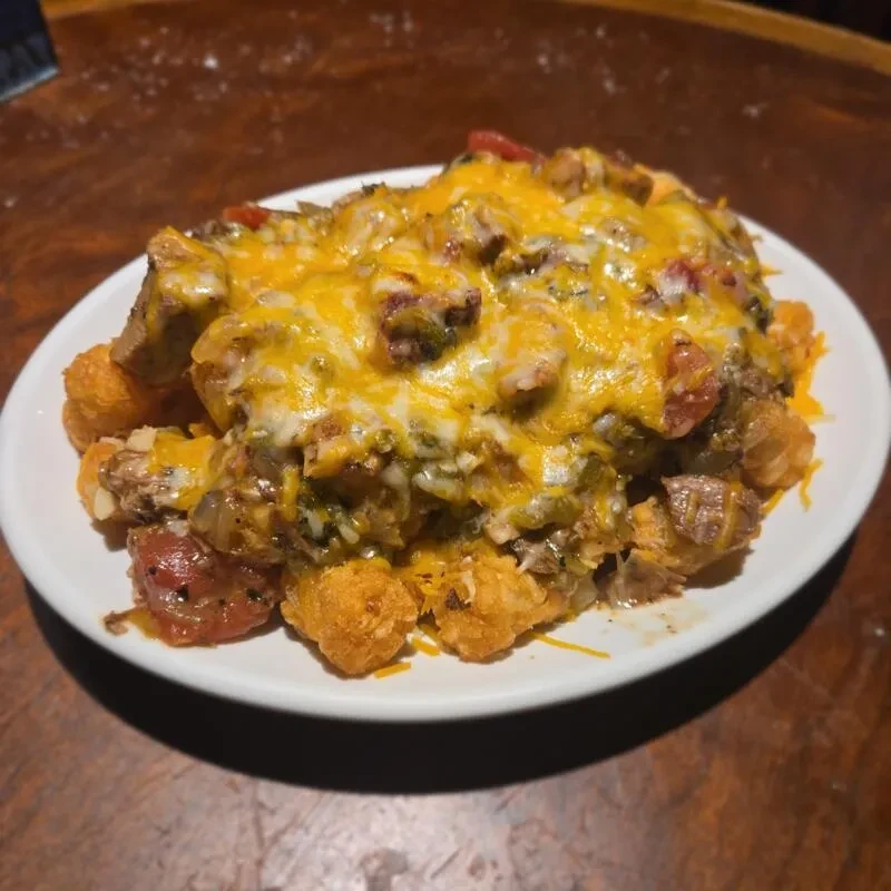 Tater tots topped with chopped meat, tomatoes, green peppers, melted cheese.