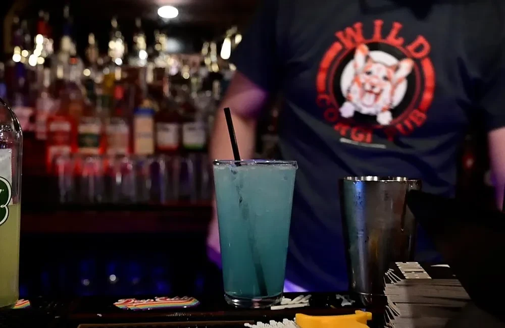 Bright blue drink, straw, person in a Wild Corgi Club shirt.
