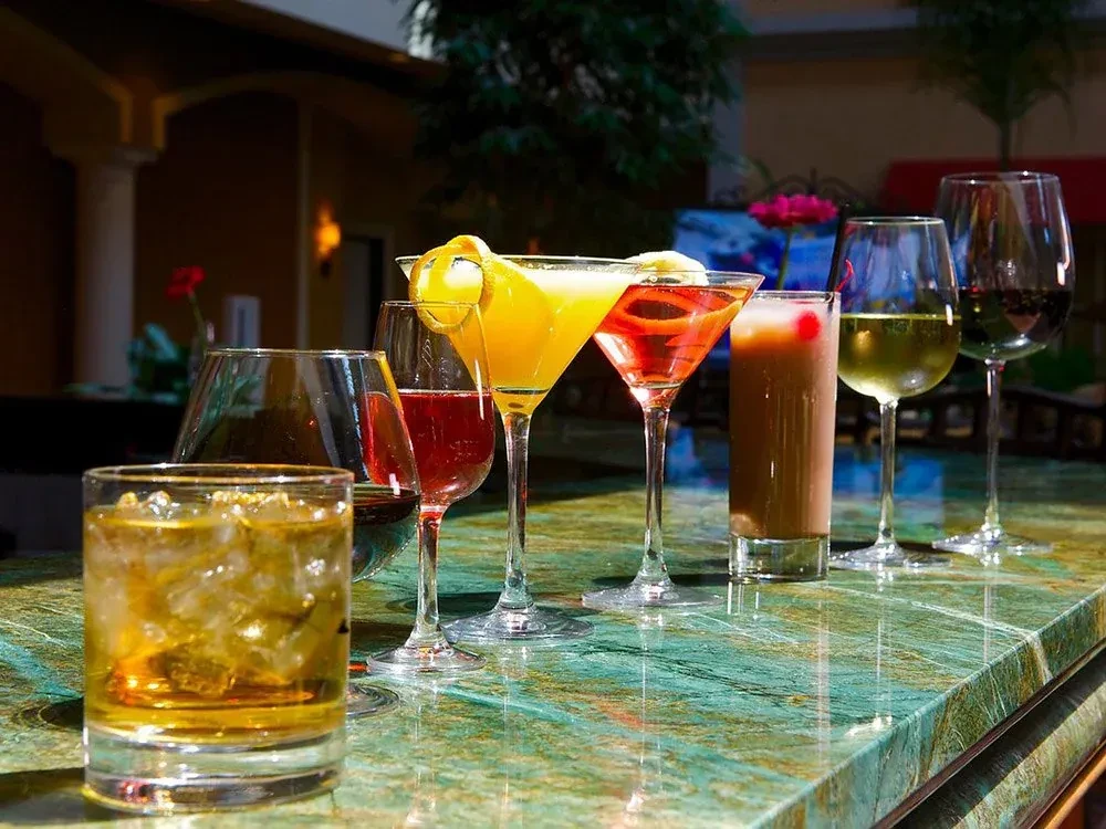 Assorted cocktails and wines on a polished green marble counter.