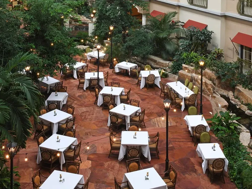 Expansive, elegant resort dining area with lush greenery and warm lighting.