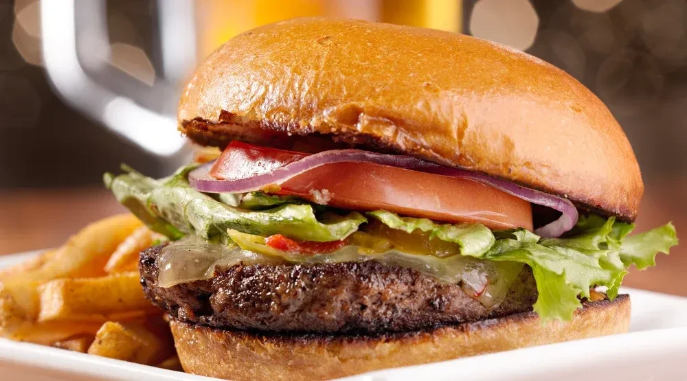 Brioche beef burger with melted cheese, vegetables, and golden fries.