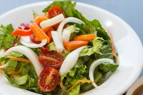 Fresh salad with lettuce, tomatoes, carrots, onions, and bell pepper.