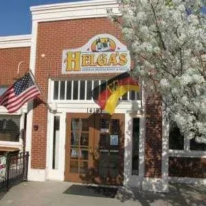 Red brick Helga's German Restaurant with flags and a large blooming tree.