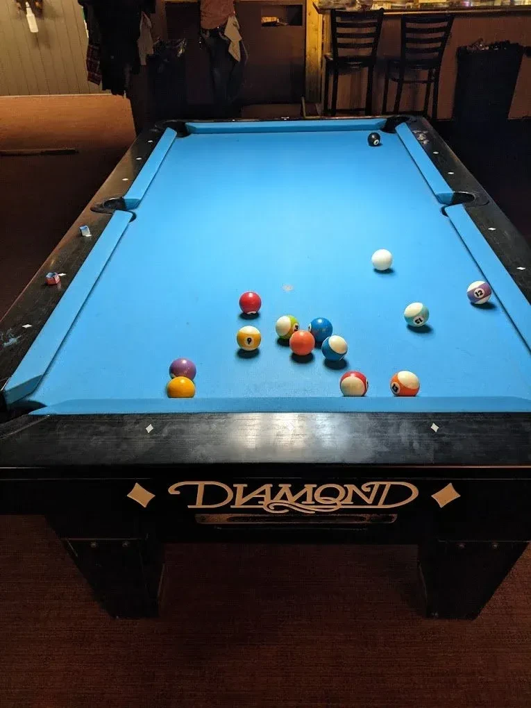 Blue billiard table with pool balls and "DIAMOND" logo in a bar.