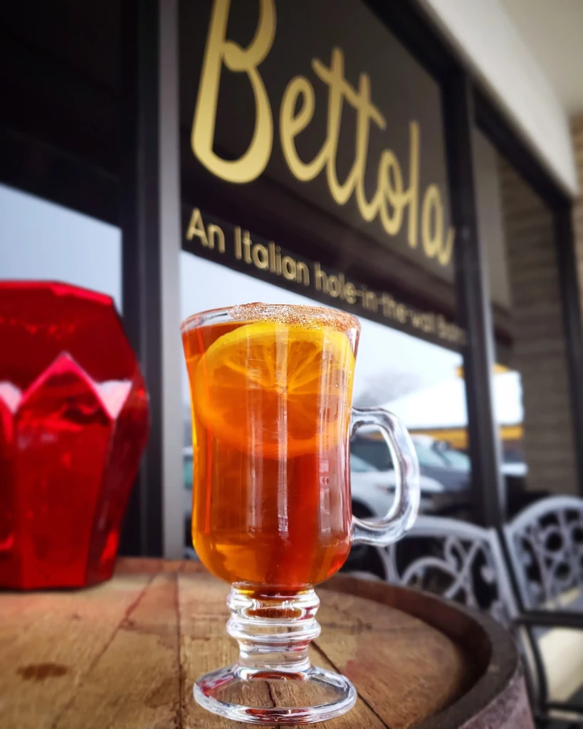 Sugar-rimmed mug with amber drink and orange slices on a wooden surface.