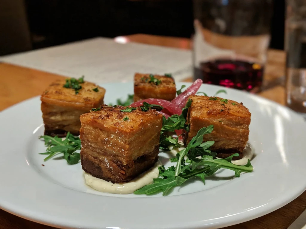Four golden-brown crispy layered appetizers with sauce, greens, and onion.