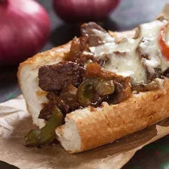 Cheesesteak with meat, green peppers, onions, melted cheese, and tomato.