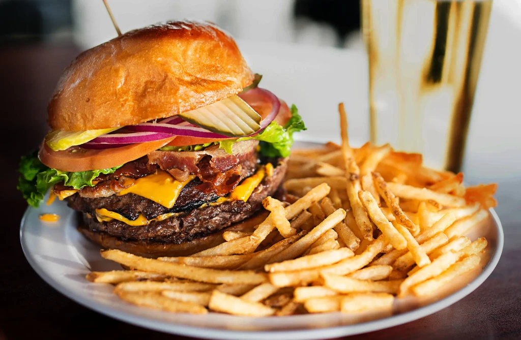 Double cheeseburger with bacon, lettuce, tomato, red onion, pickles, and fries.