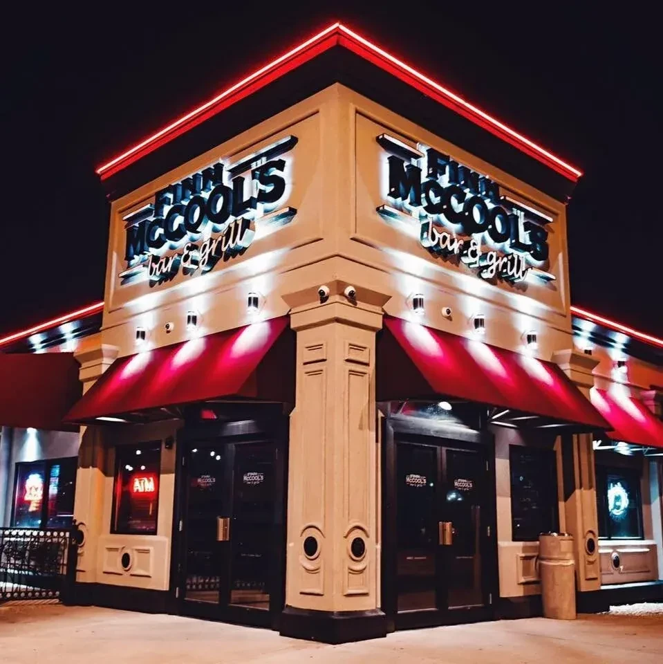 Lit Finn McCool's Bar & Grill building with red awnings at night.