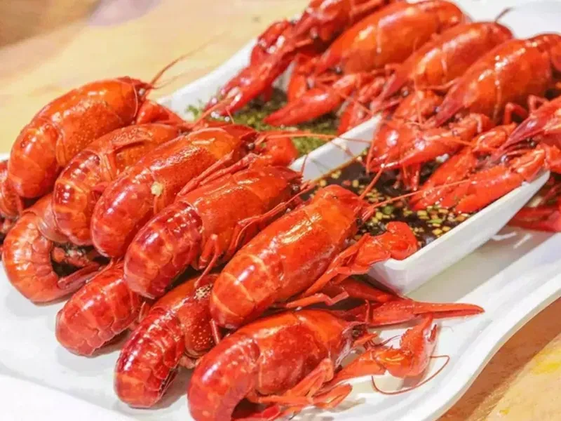 Generous serving of bright red cooked crawfish with a dark dipping sauce.