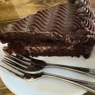 Layered chocolate cake slice with wavy frosting and two forks.