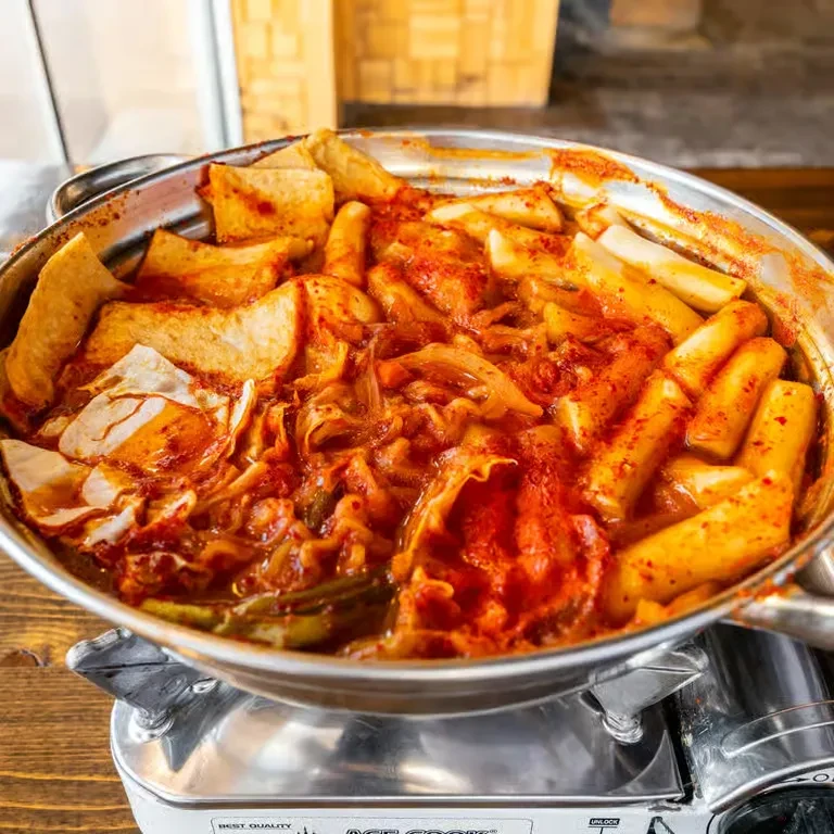 Bubbling Korean hot pot with rice cakes on a gas stove.