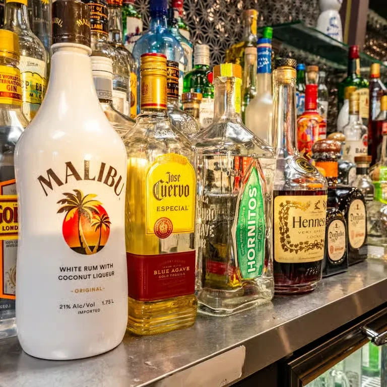 Malibu, Jose Cuervo, Hornitos, and Hennessy bottles on a well-stocked bar.
