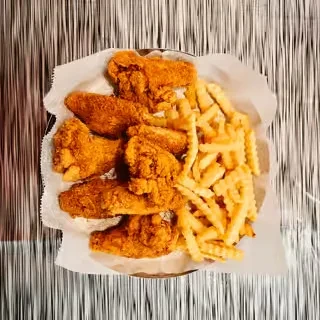 A basket of golden fried chicken wings and crinkle-cut fries.