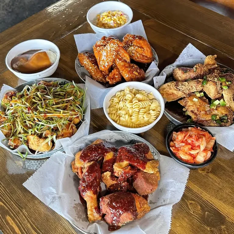 Different fried chicken styles and sides on a rustic wooden table.