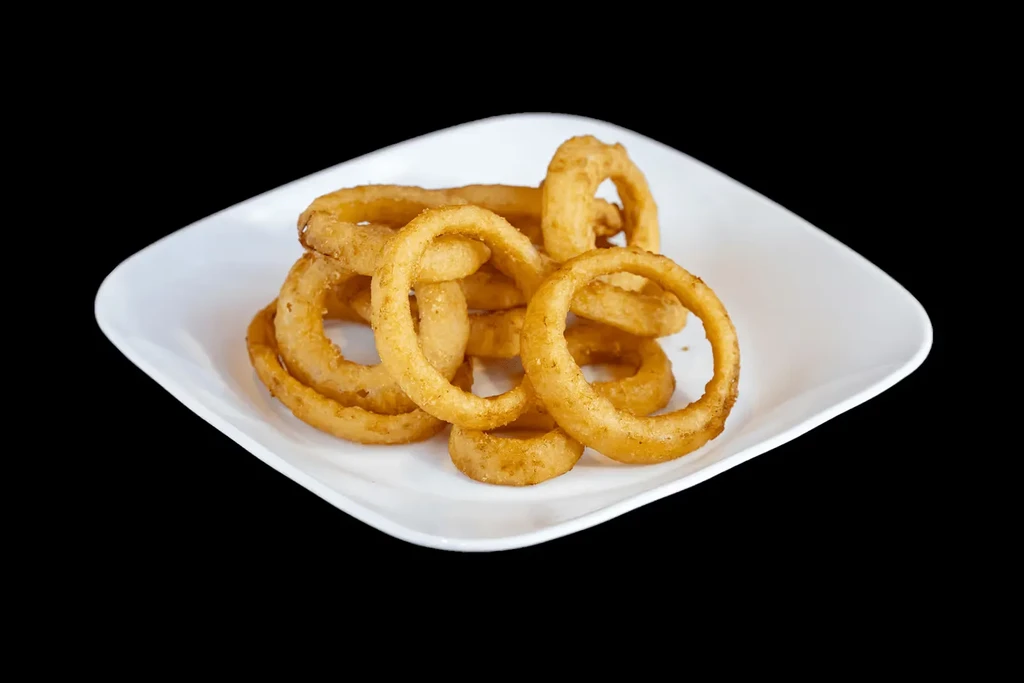 A pile of golden-brown, crispy onion rings on a white plate.