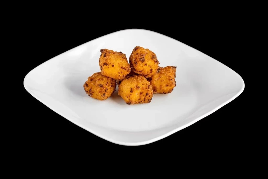Six golden-brown crispy fried items on a white plate, black background.
