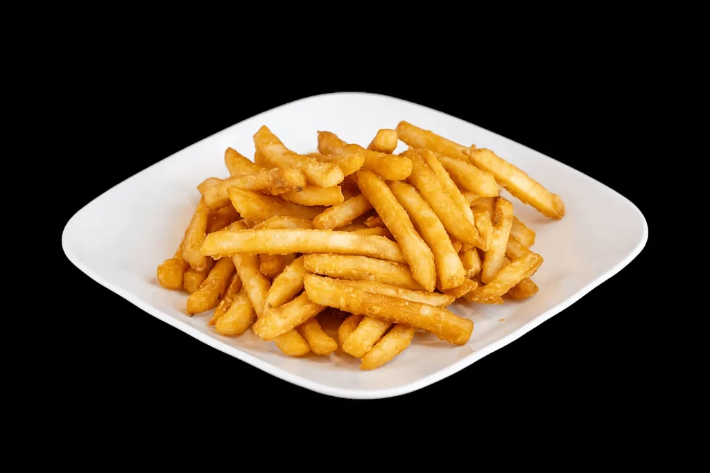 Crispy golden french fries on a white plate with a black background.