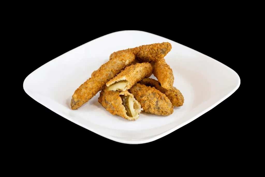 Golden-brown fried pickles with a pale green interior on a white plate.