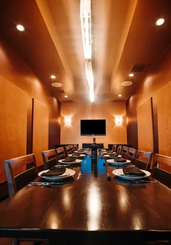Well-appointed private dining room with long, set wooden table and TV.