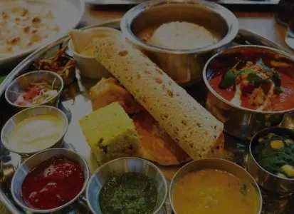 An Indian thali with curries, rice, dhokla, chutneys, and flatbread.