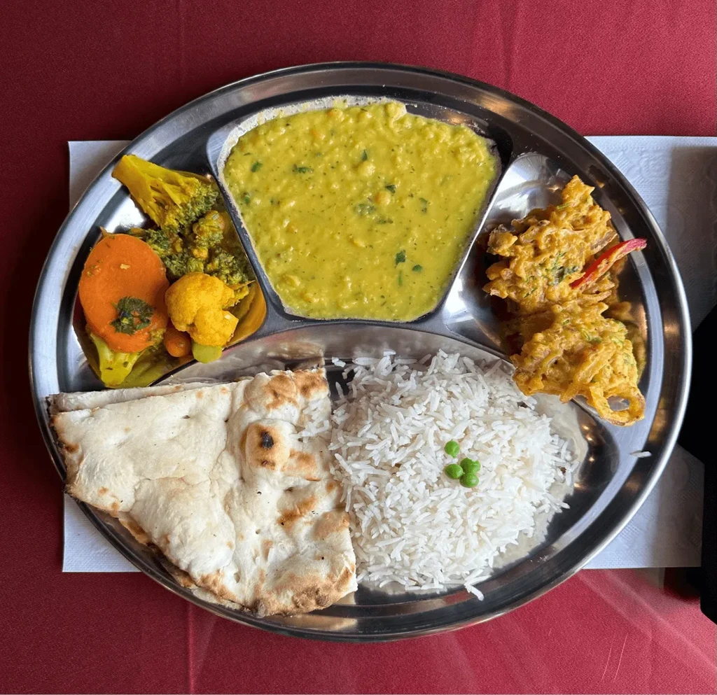 Traditional Indian thali meal with assorted dishes on a steel plate.