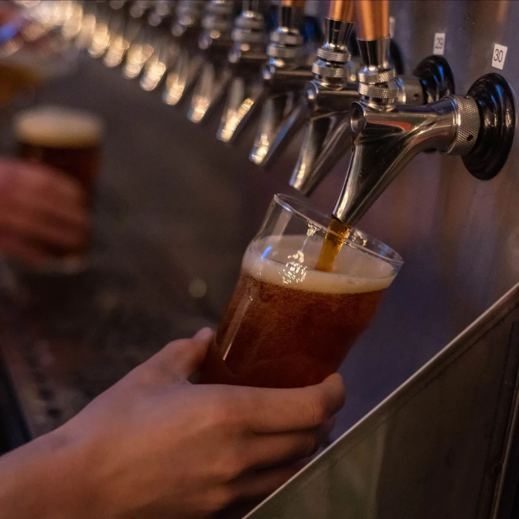 Close-up: Amber beer pouring into a glass from a bar tap.