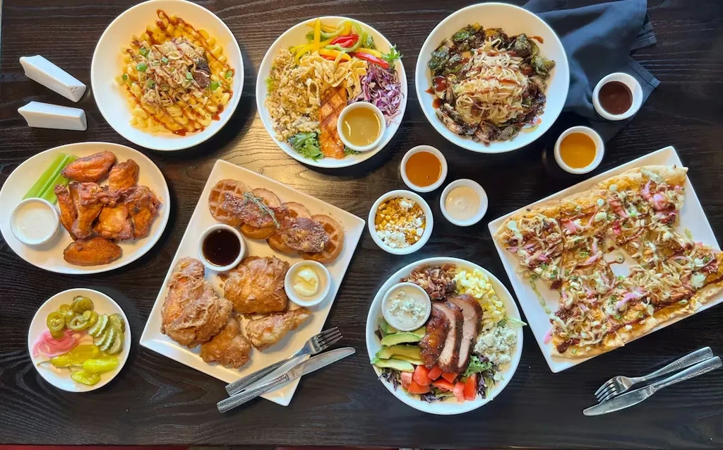 Flat lay of a dark table covered with diverse restaurant dishes.
