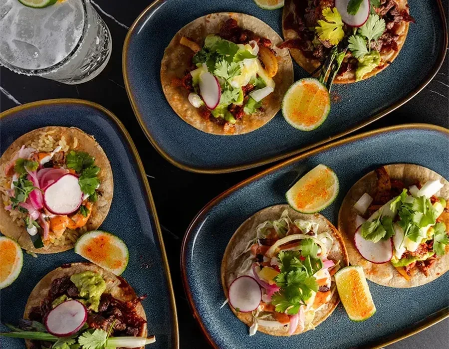 Vibrant overhead shot of gourmet tacos with varied toppings and spiced limes.
