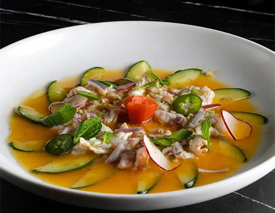 Colorful seafood ceviche, top-down, with cucumber and tomato flower.
