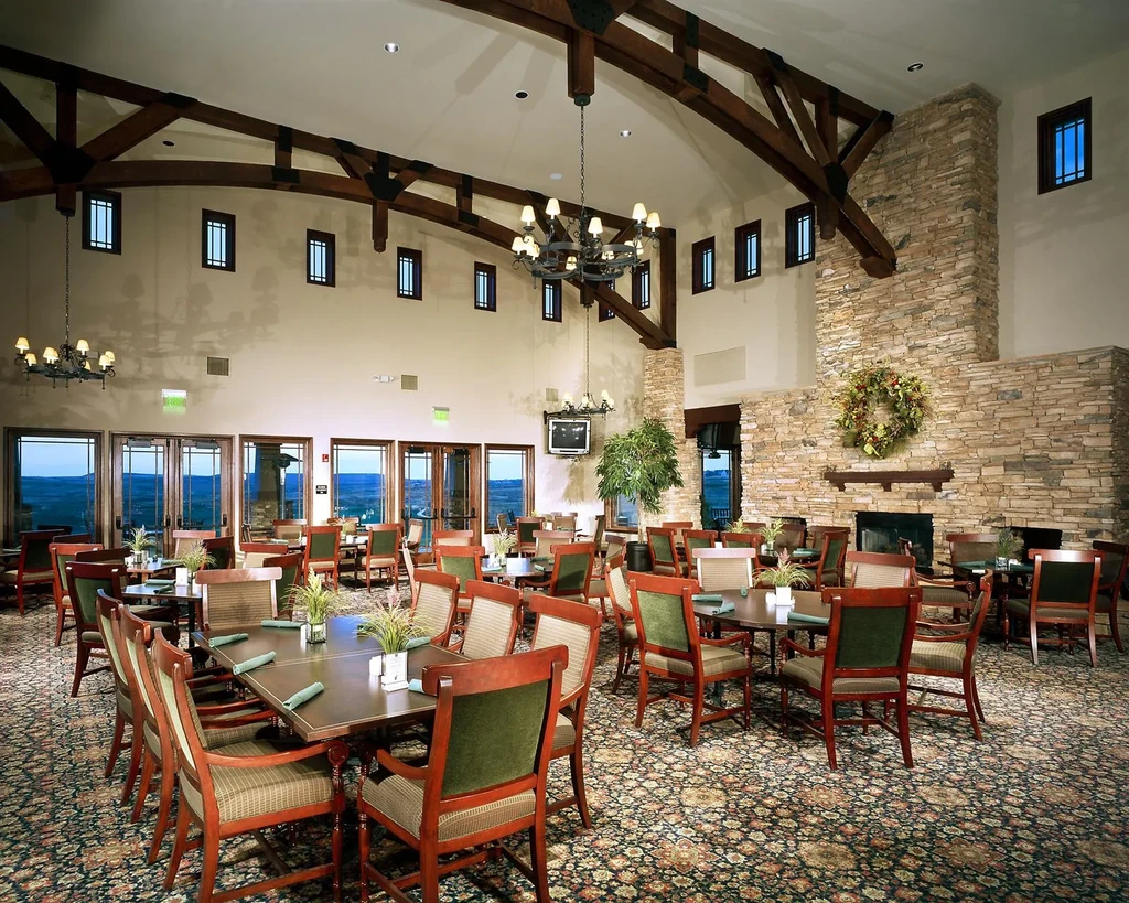 Spacious restaurant dining room with stone fireplace, beams, valley views.