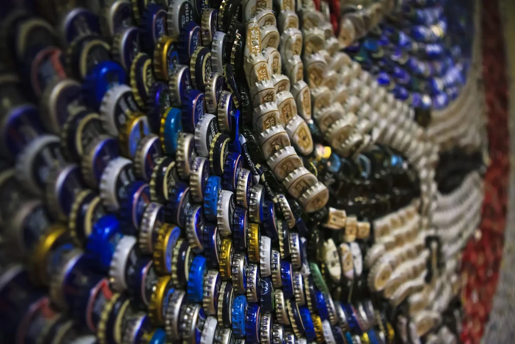 Art mosaic made from layered blue, silver, and gold bottle caps.