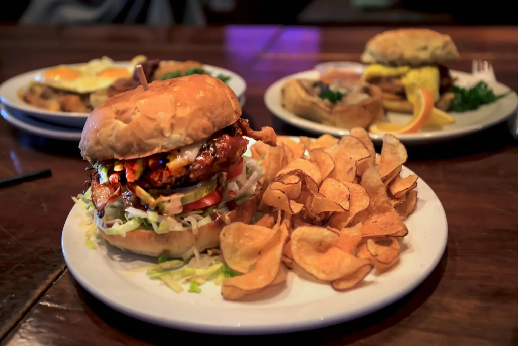 Large fried chicken burger with cheese, bacon, and crispy potato chips.