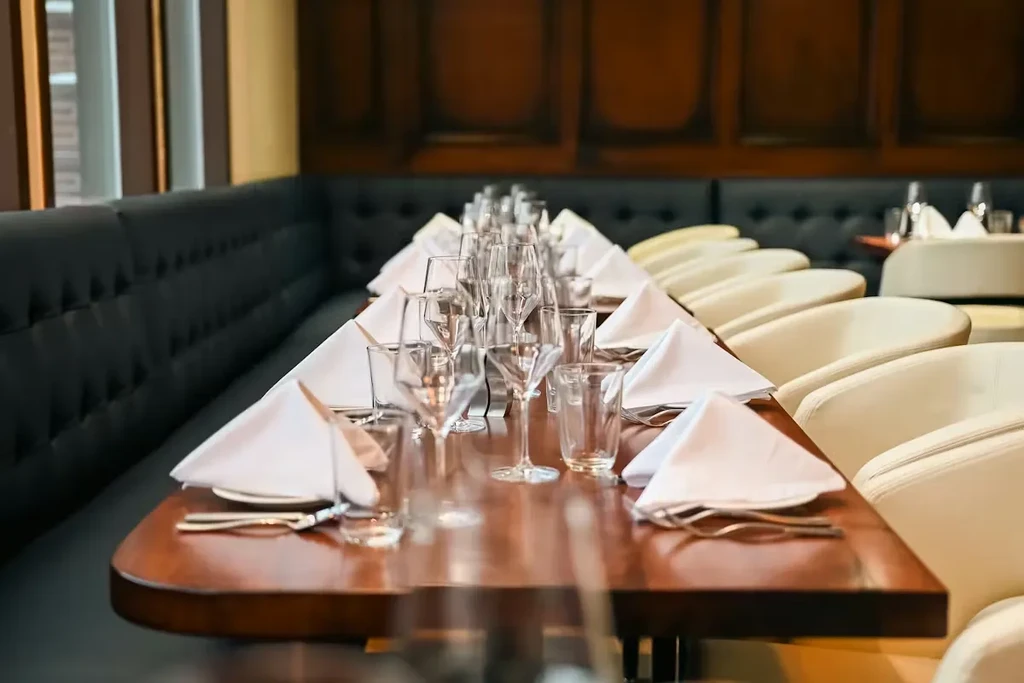 Meticulously set dark wood dining table in upscale restaurant, no people.
