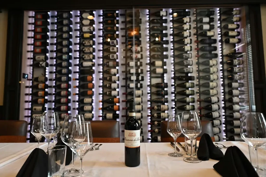 Sophisticated restaurant interior with a backlit wine wall and set table.